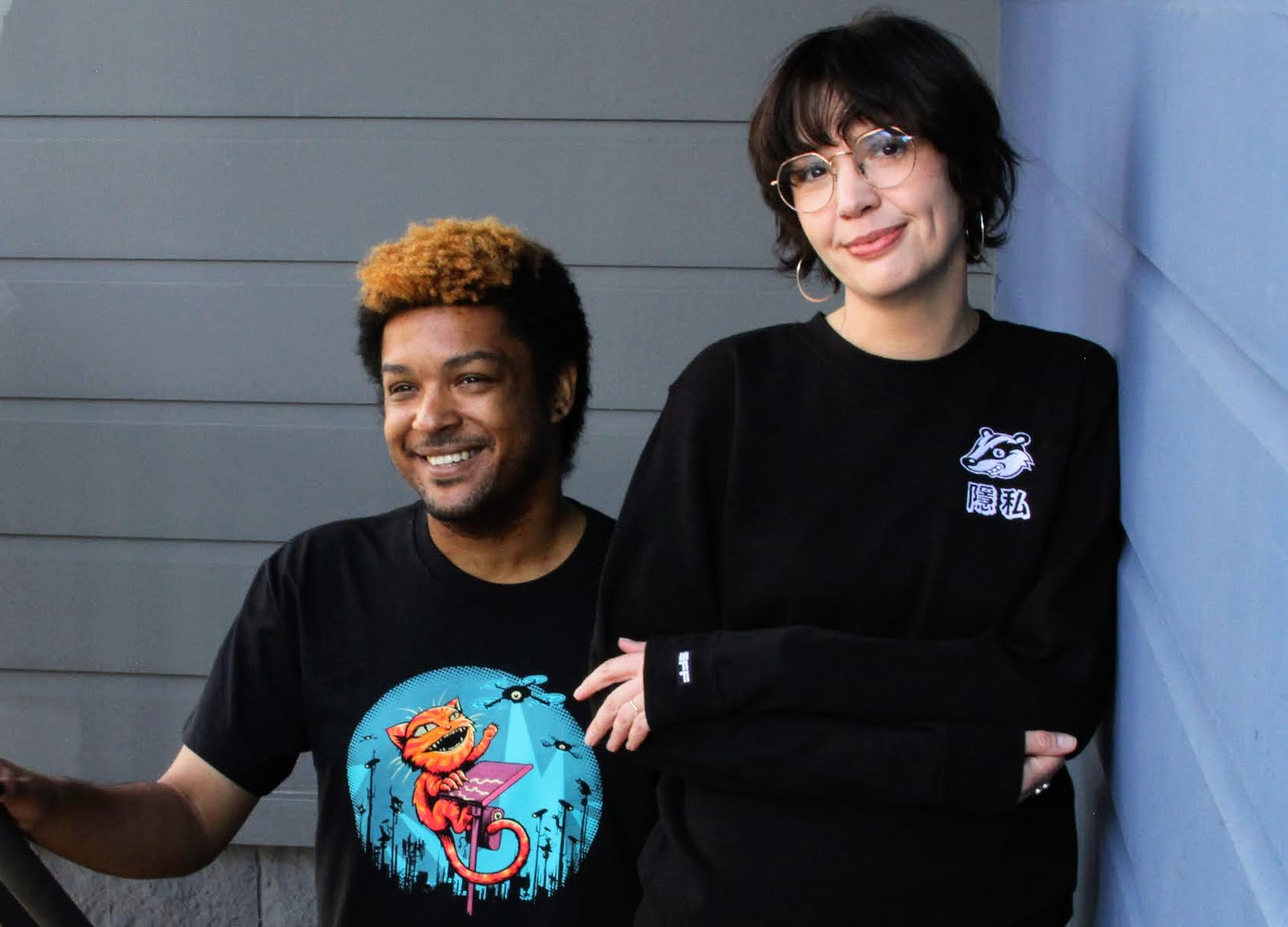 A person wears an EFF Claw Back member t-shirt on the left. A person on the right wears a black sweatshirt with the Privacy Badger mascot on the chest.